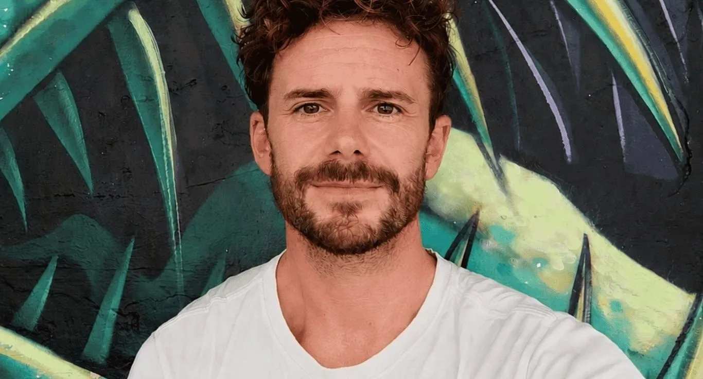 Portrait of Scott Finch in front of a green and yellow mural
