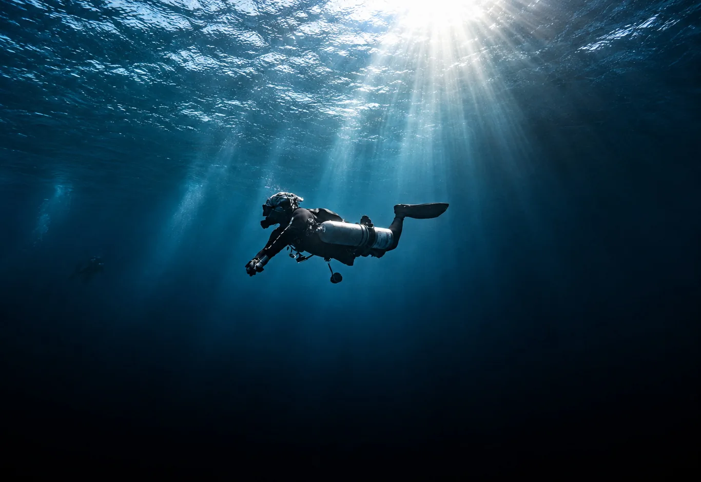 Scott Finch sidemount diving beneath sunbeams in deep blue water in Gran Canaria